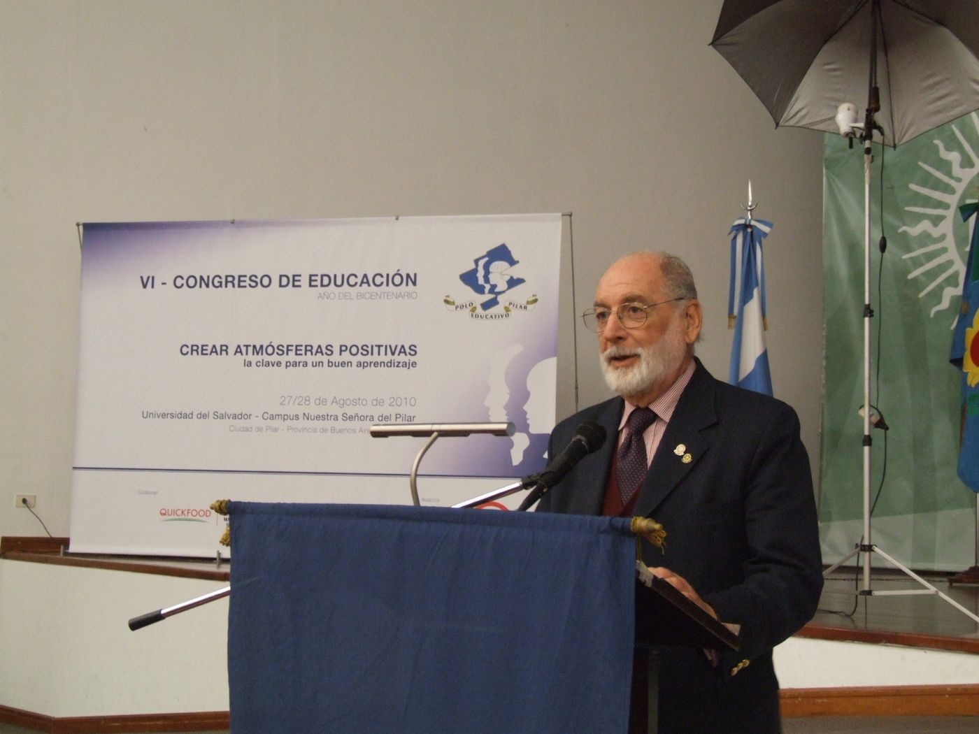 Un orador habla desde el atril, junto al cartel del Congreso de Educación del 27 y 28 de agosto de 2010
